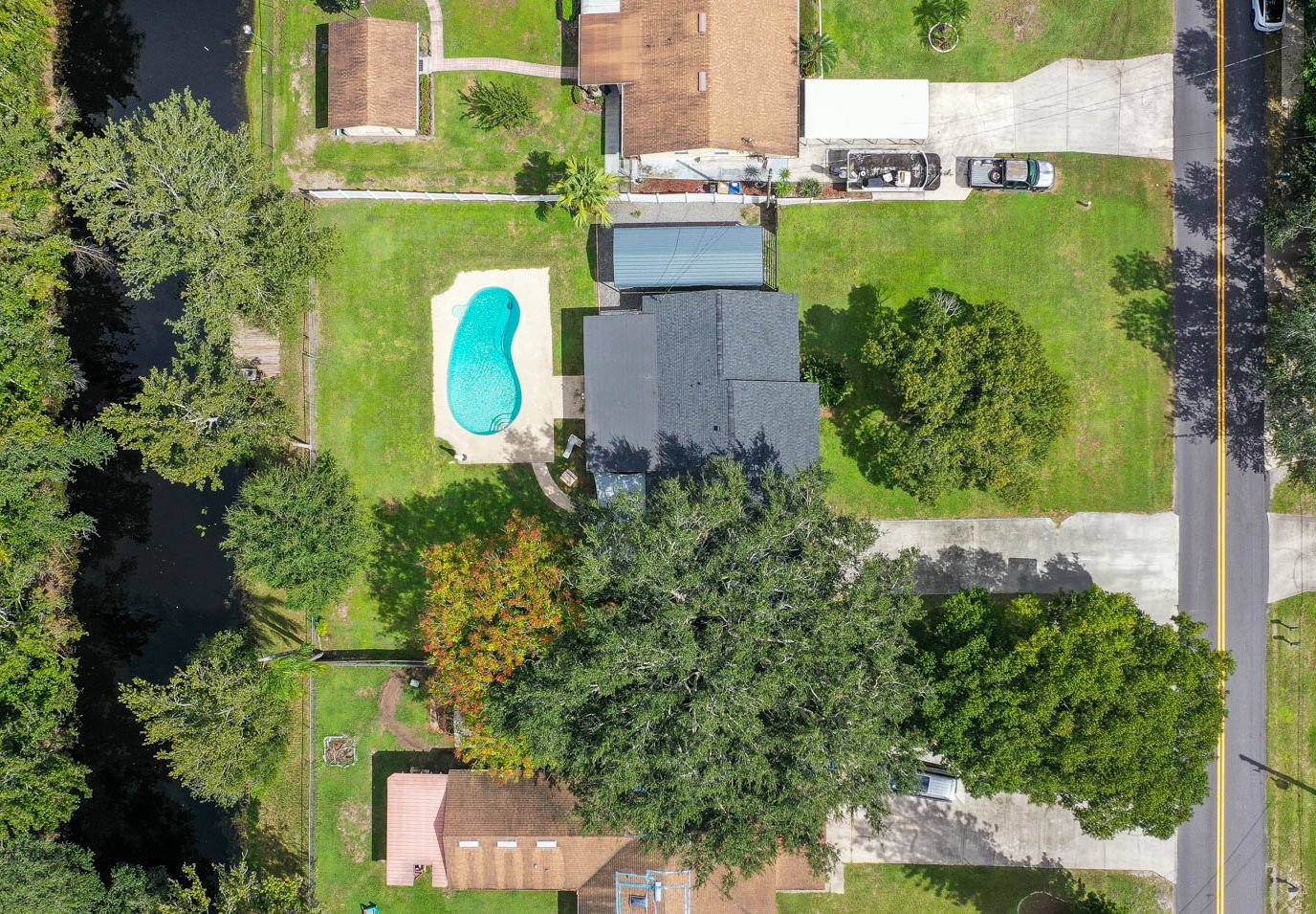 drone shot of home with pool and canal and surrounding trees